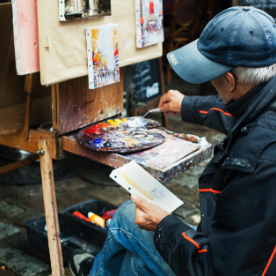 Older man doing painting on a canvas