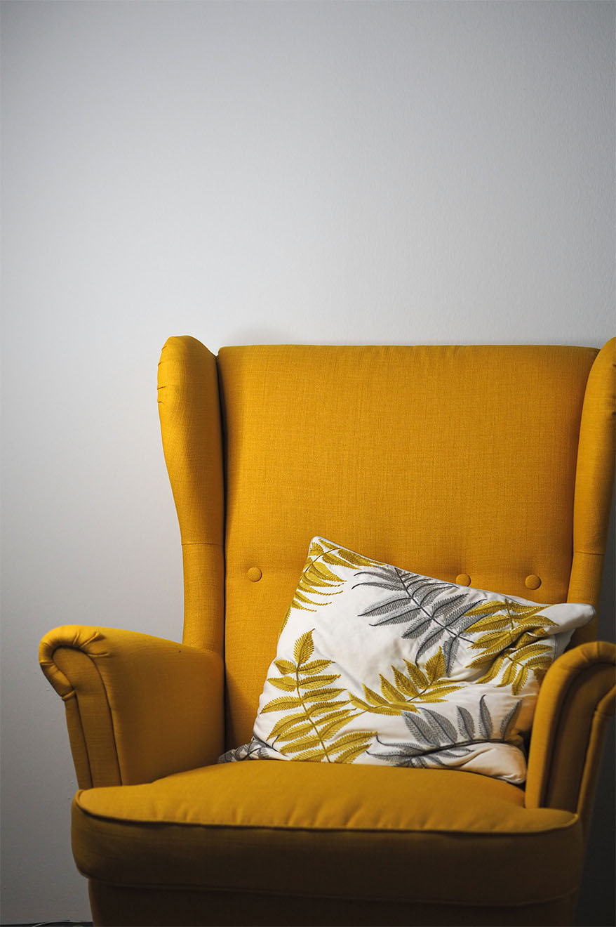 a yellow armchair with a cushion on it