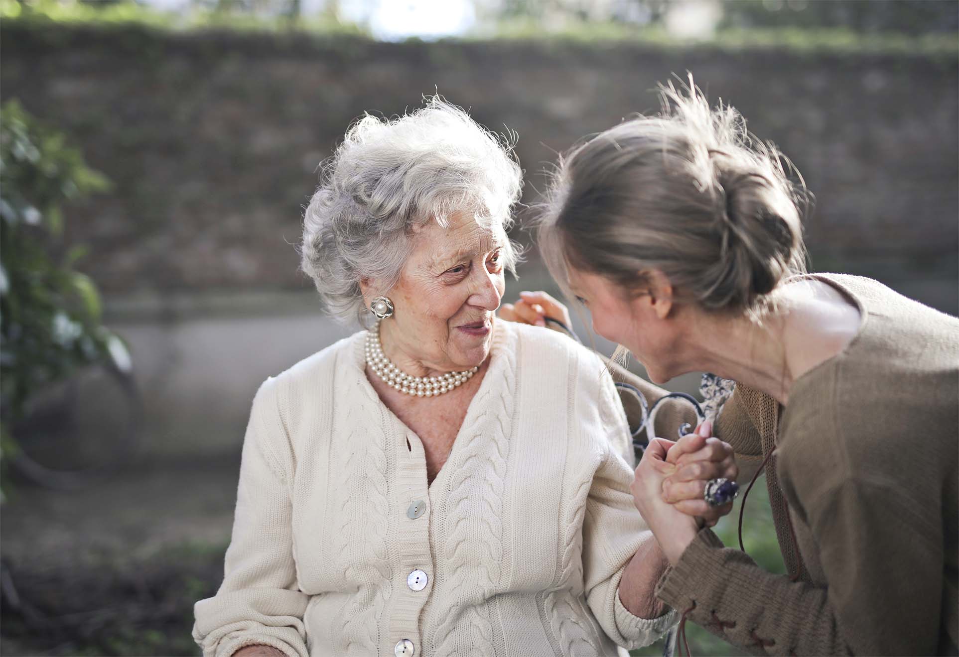 resident and their loved one holding hands and talking on a bench