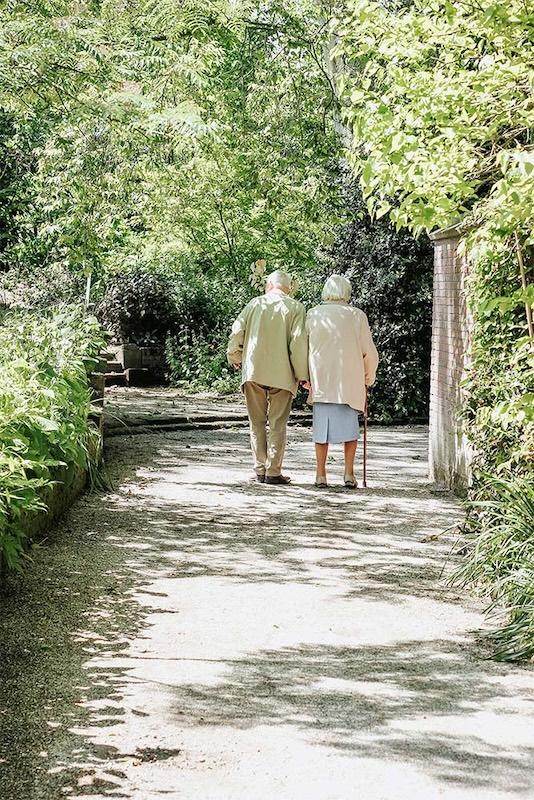 two older adults on a walk together on a path in the forest